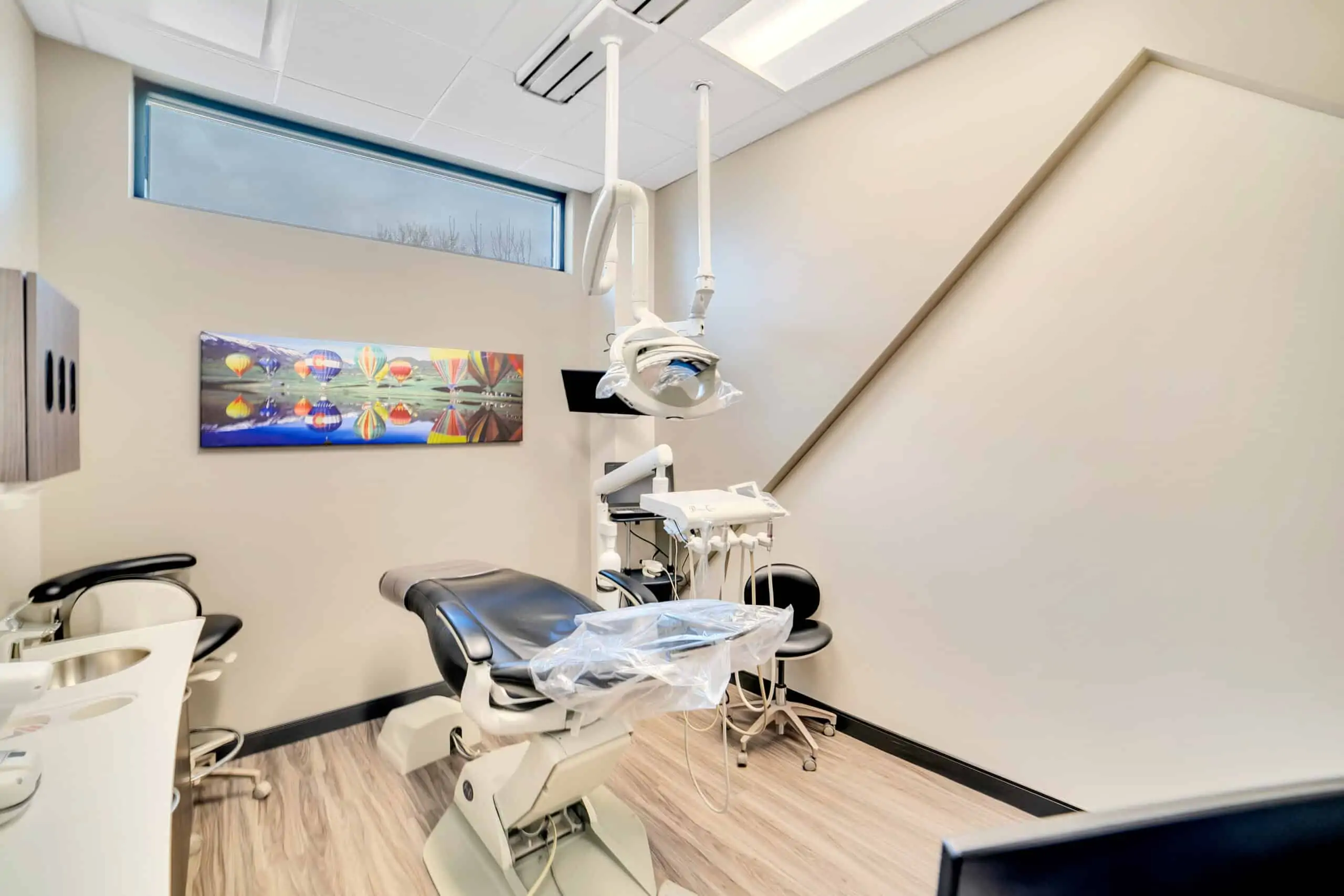 A patient examination room with a dental chair and other dental equipment at Signature Dentistry of Arvada