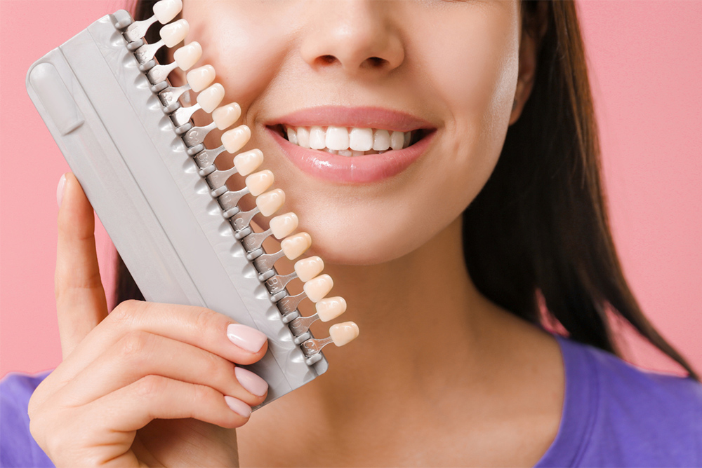 A patient holding different types of dental veneers